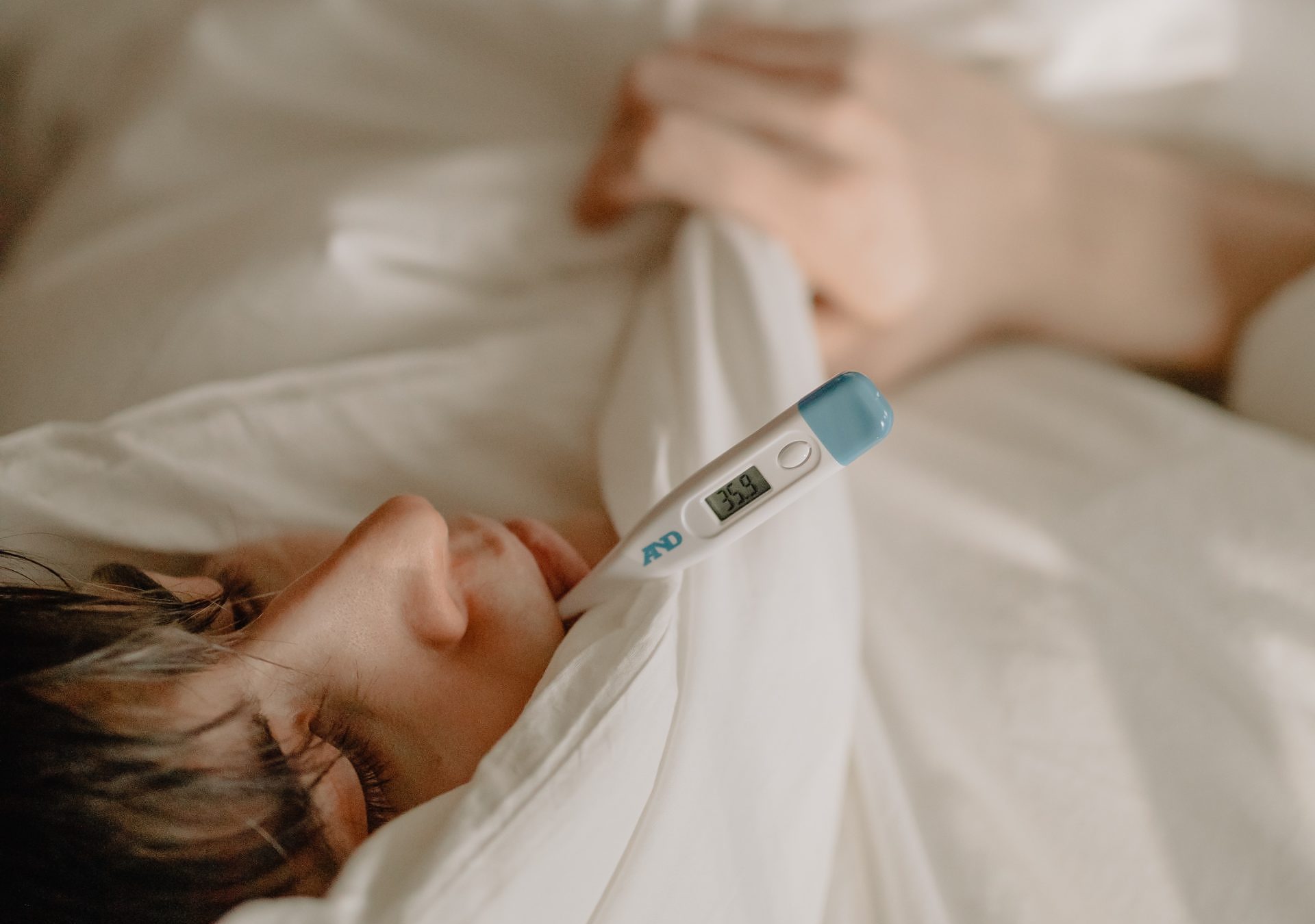 cold and flu Sick person lying in bed with a thermometer