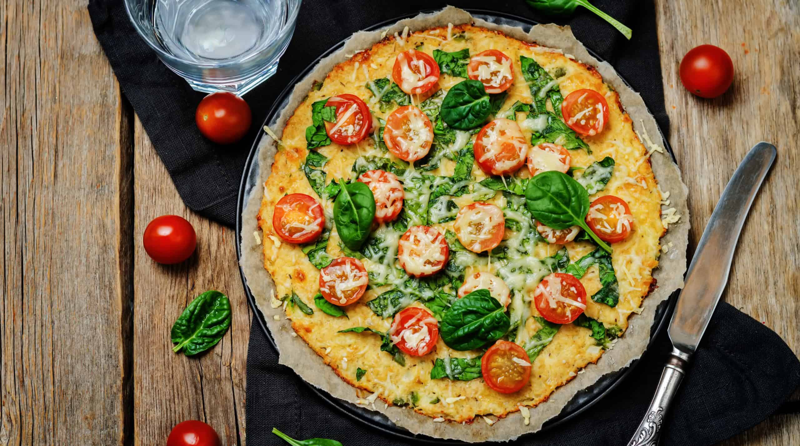 Cauliflower pizza crust with tomato and spinach